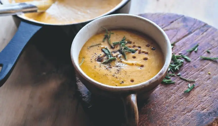 gluten-free butternut squash soup in a bowl with herb garnish