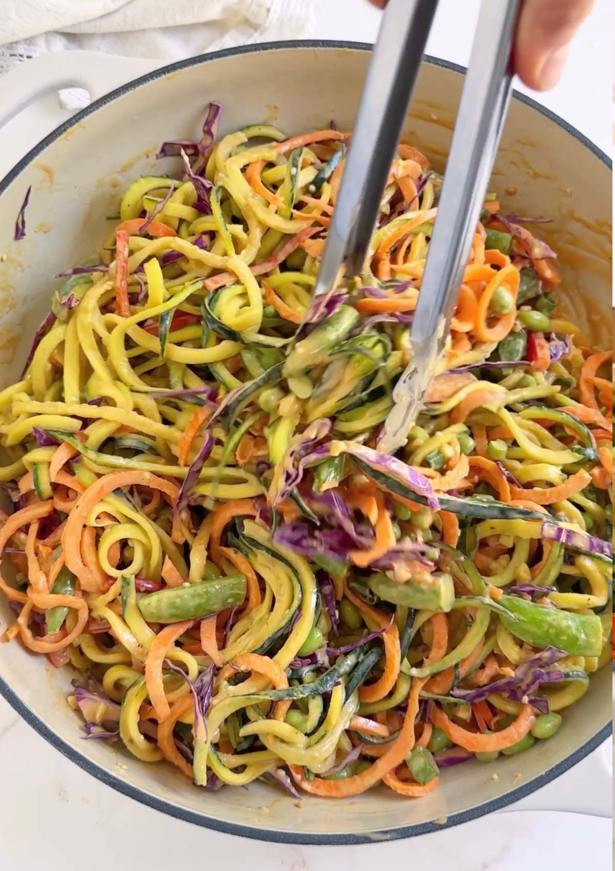 Bowl of fresh zucchini noodles with peanut sauce.