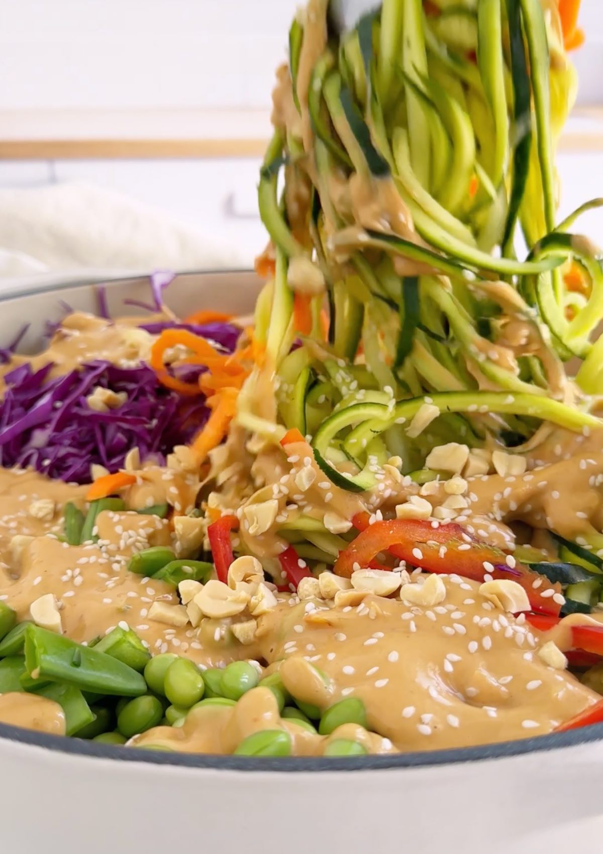 Pulling up zucchini noodles from a bowl of fresh zoodles. 