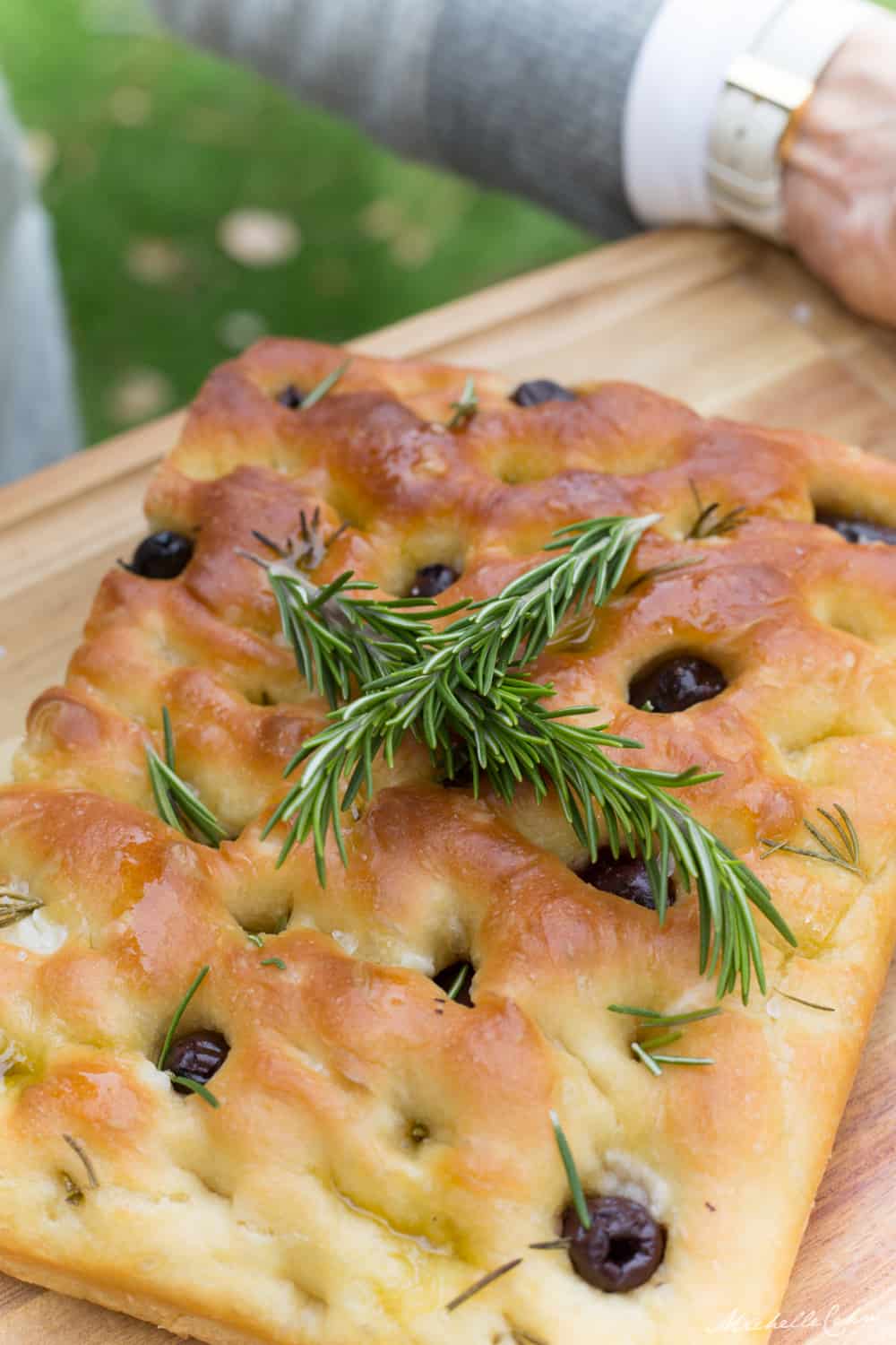 vegan focaccia bread with rosemary sprigs on top and olive and rosemary focaccia toppings
