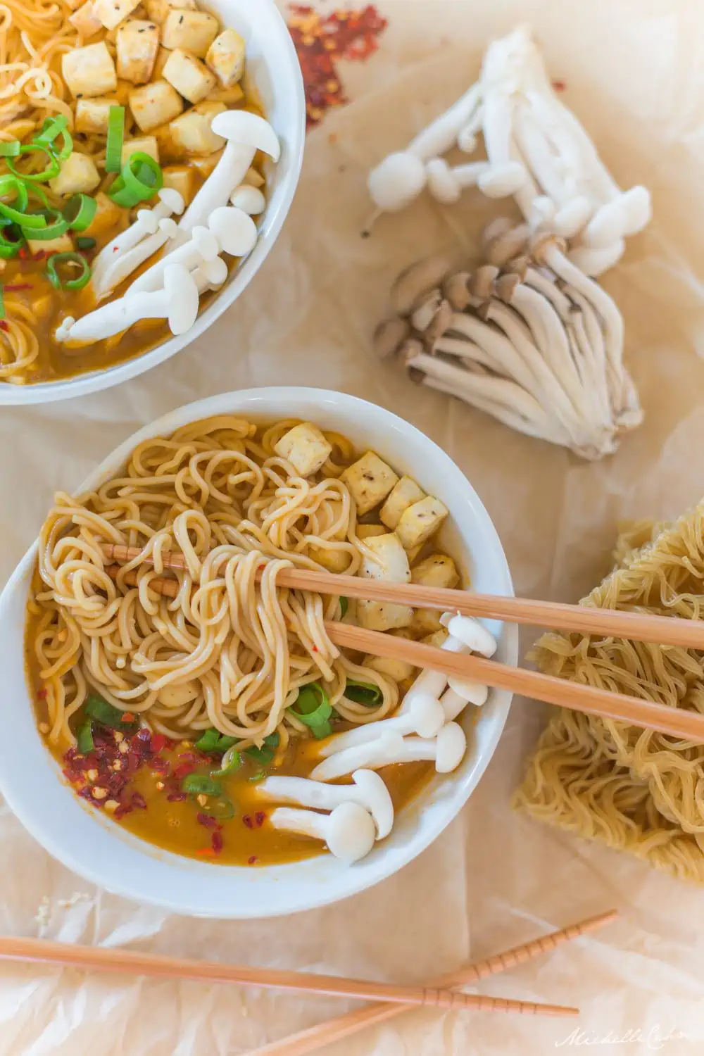 Best vegan ramen soup served in a white bowl with rice noodles topped with mushrooms, tofu, red pepper flakes