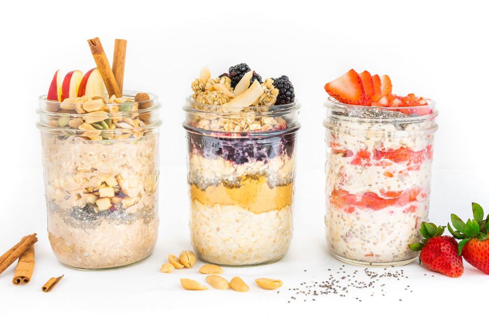 Overnight oats in jars with different toppings like peanut butter and jelly, strawberries, and apple pie.