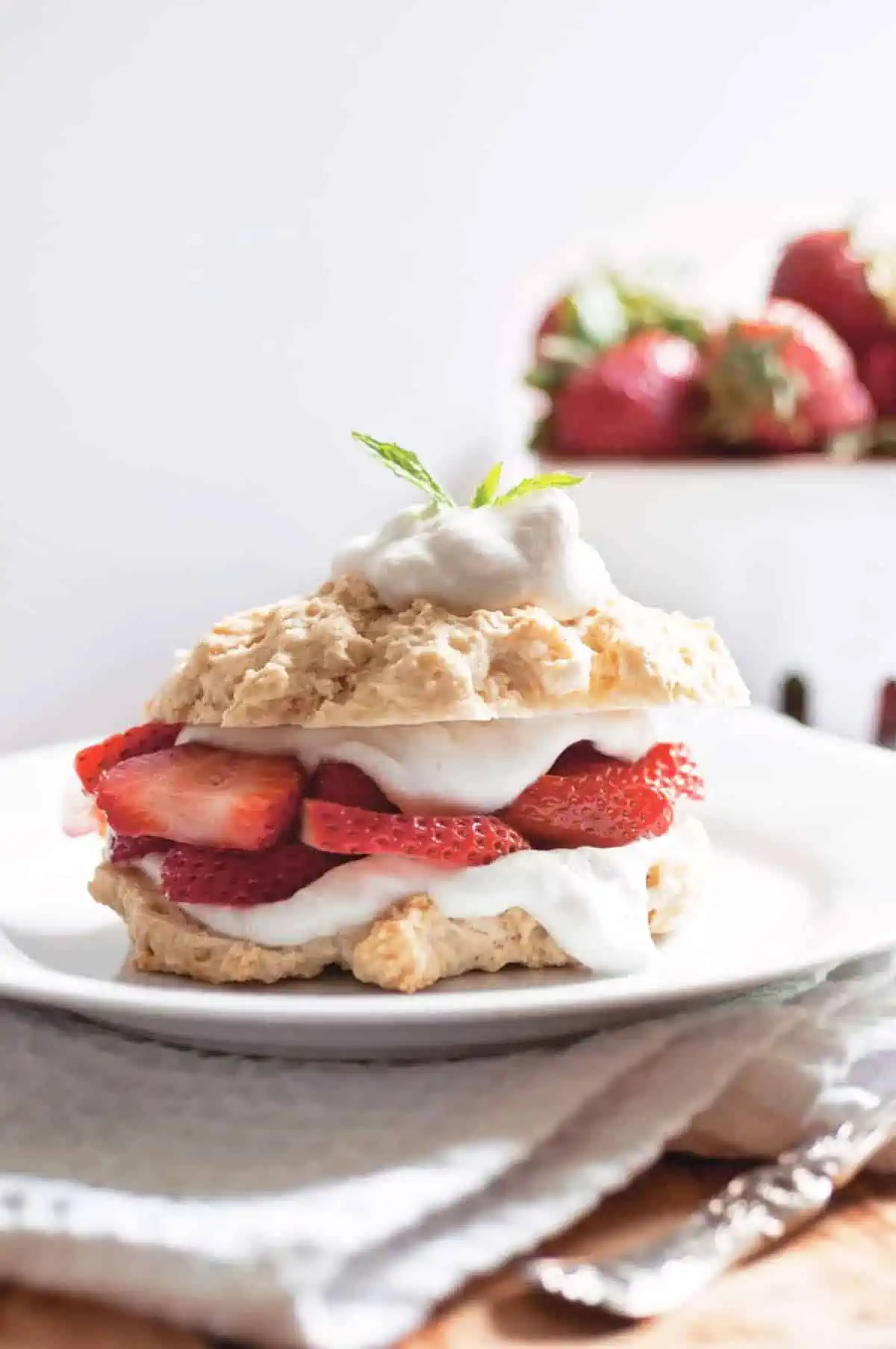 Vegan strawberry shortcake on a serving plate, topped with whipped cream.