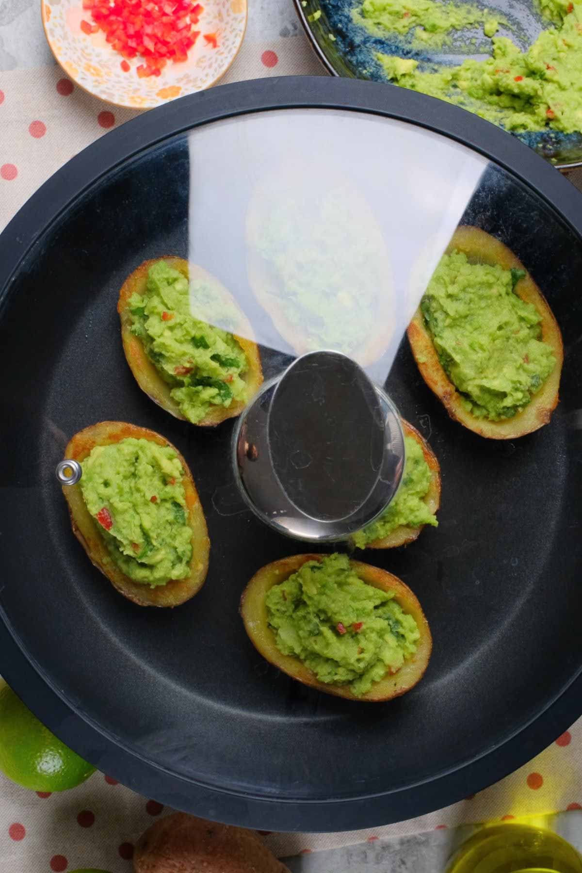 Potato skins with guacamole in a pan with a lid.
