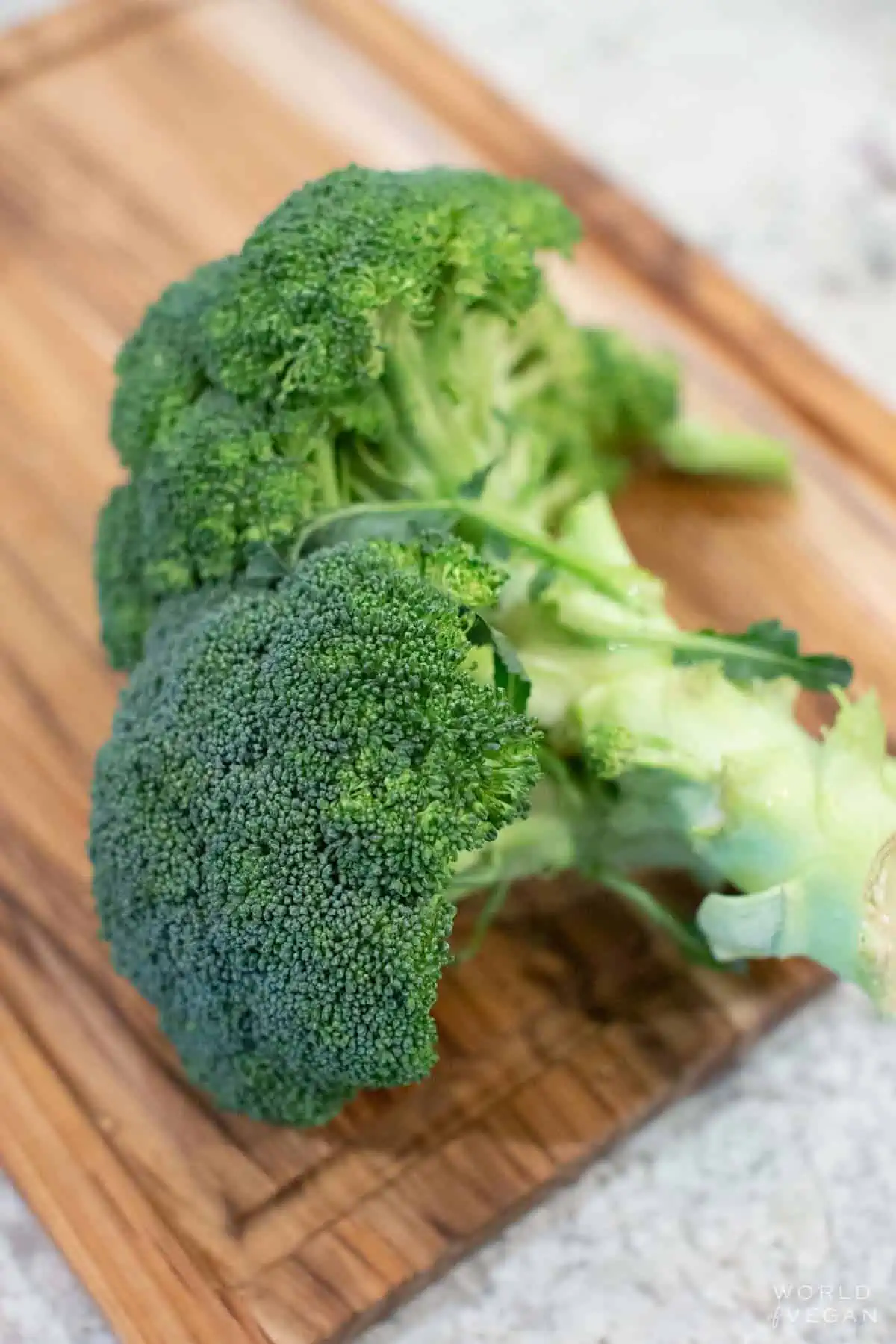 Two heads of broccoli on a cutting board.