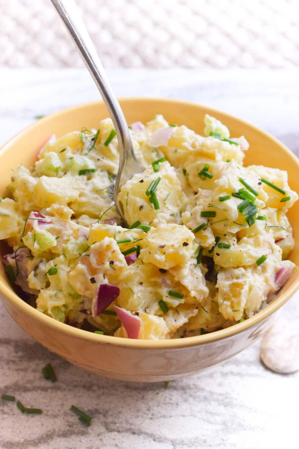 Vegan potato salad served in a bowl sprinkled with chives, a refreshing complement to vegan picnic ideas.