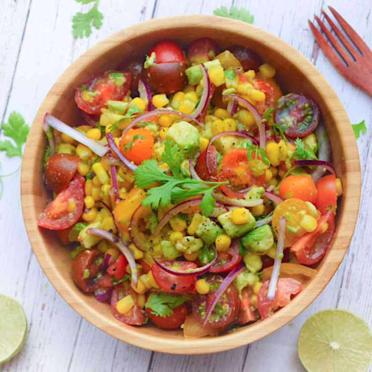 Corn and tomato salad in a serving bowl, topped with fresh cilantro leaves.