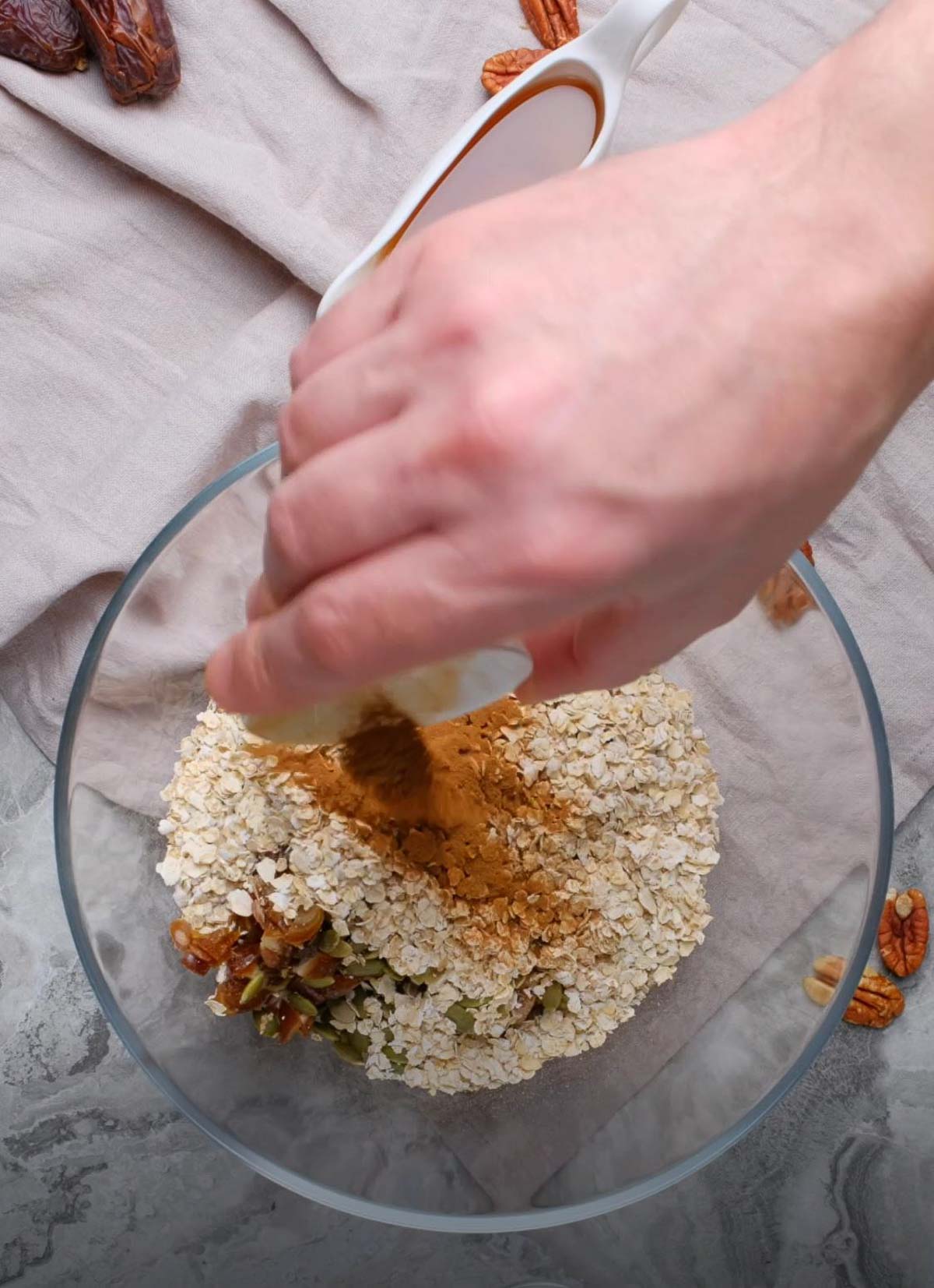 Oats, nuts, and spices in a glass prep bowl.