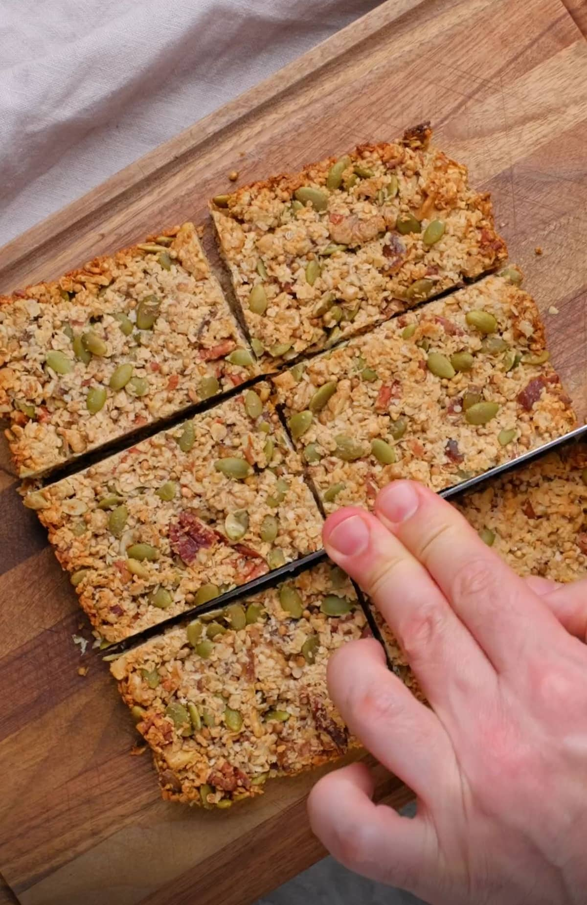 Vegan granola bars being cut by hand.