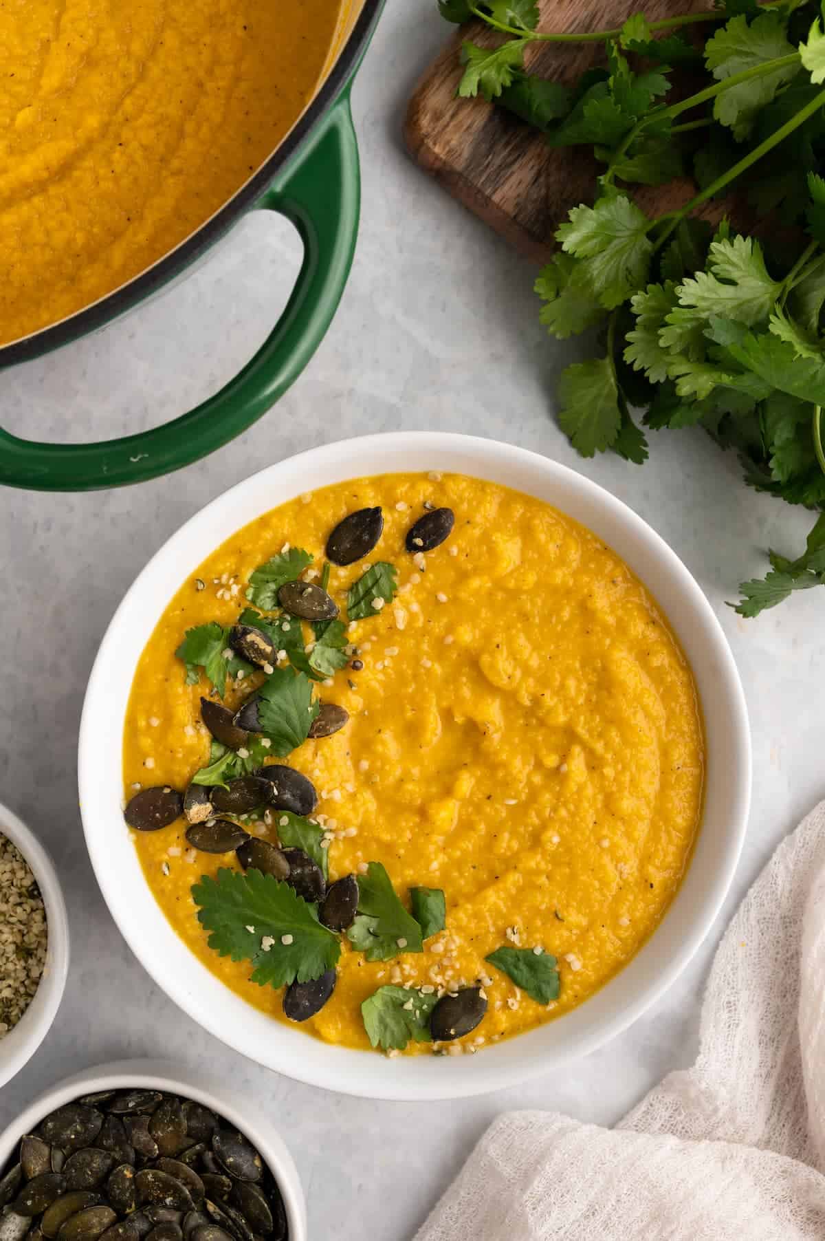 A bowl of toor dal framed by herbs, a pot, and a napkin.