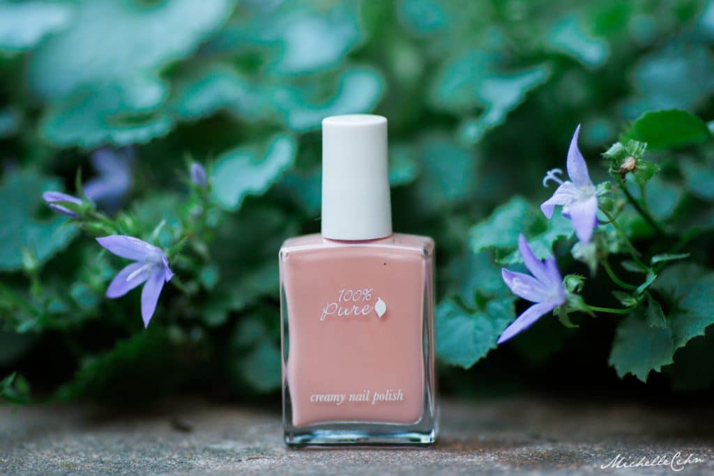 100 percent pure vegan nail polish bottle outside surrounded by flowers