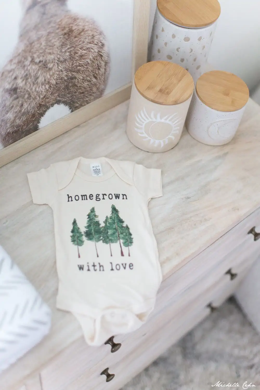 Vegan Onesie gift that says "homegrown with love" laying on a baby changing table. 