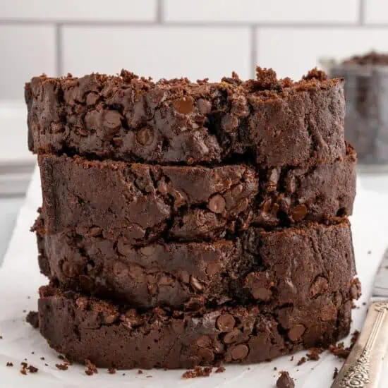 Slices of vegan chocolate zucchini bread stacked on a countertop.