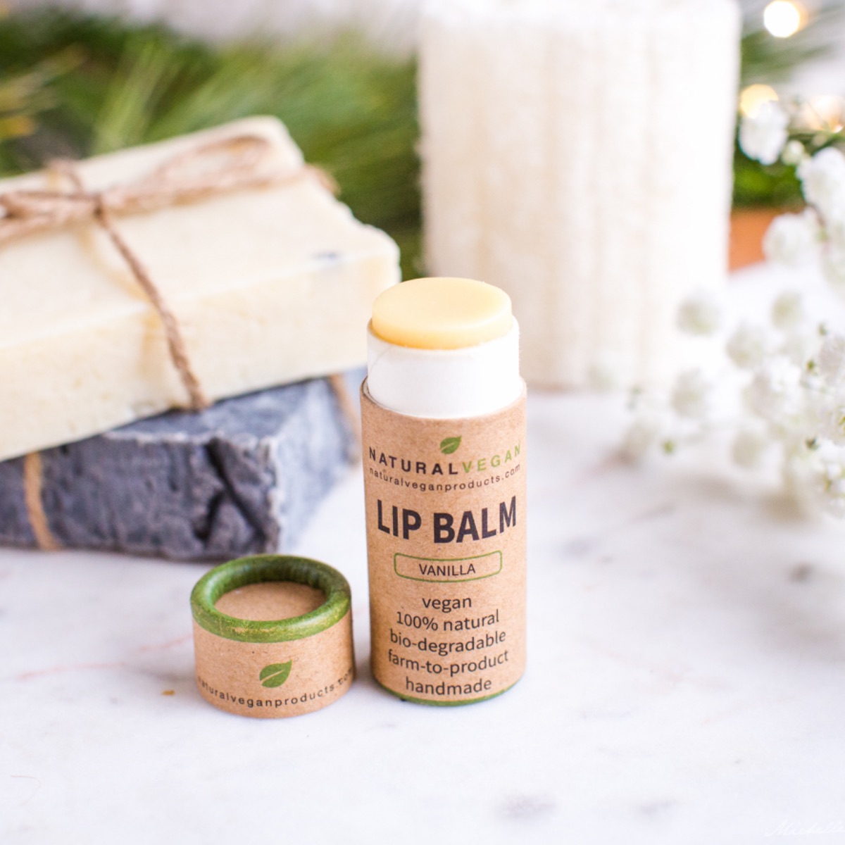 A tube of vegan lip balm in a biodegradable eco-friendly tube in a holiday gift setting.