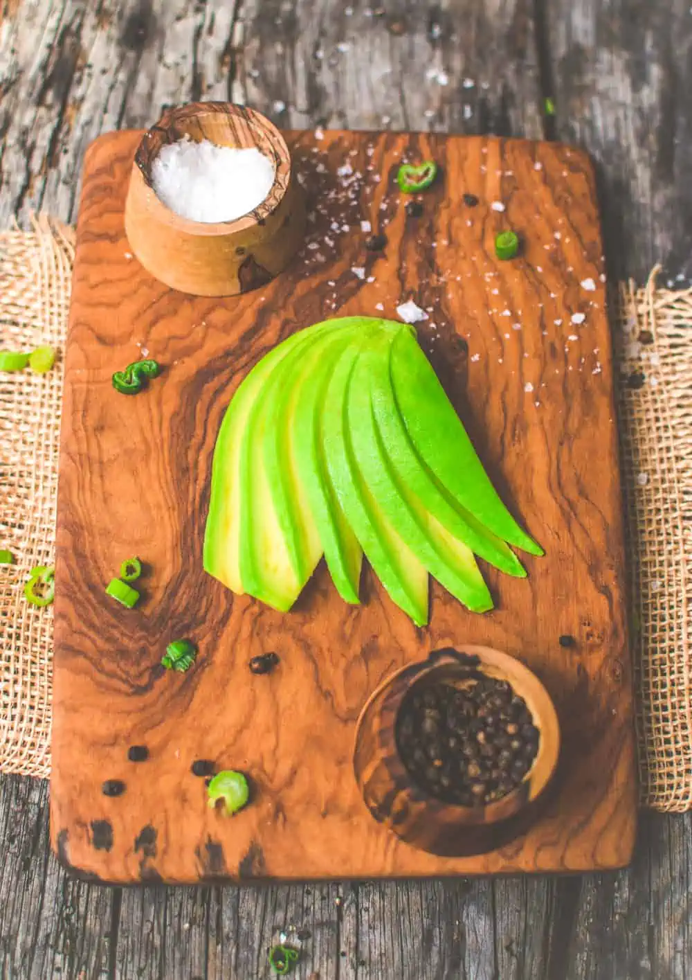 Avocado half thinly sliced and fanned out on a cutting board to look like a wing.