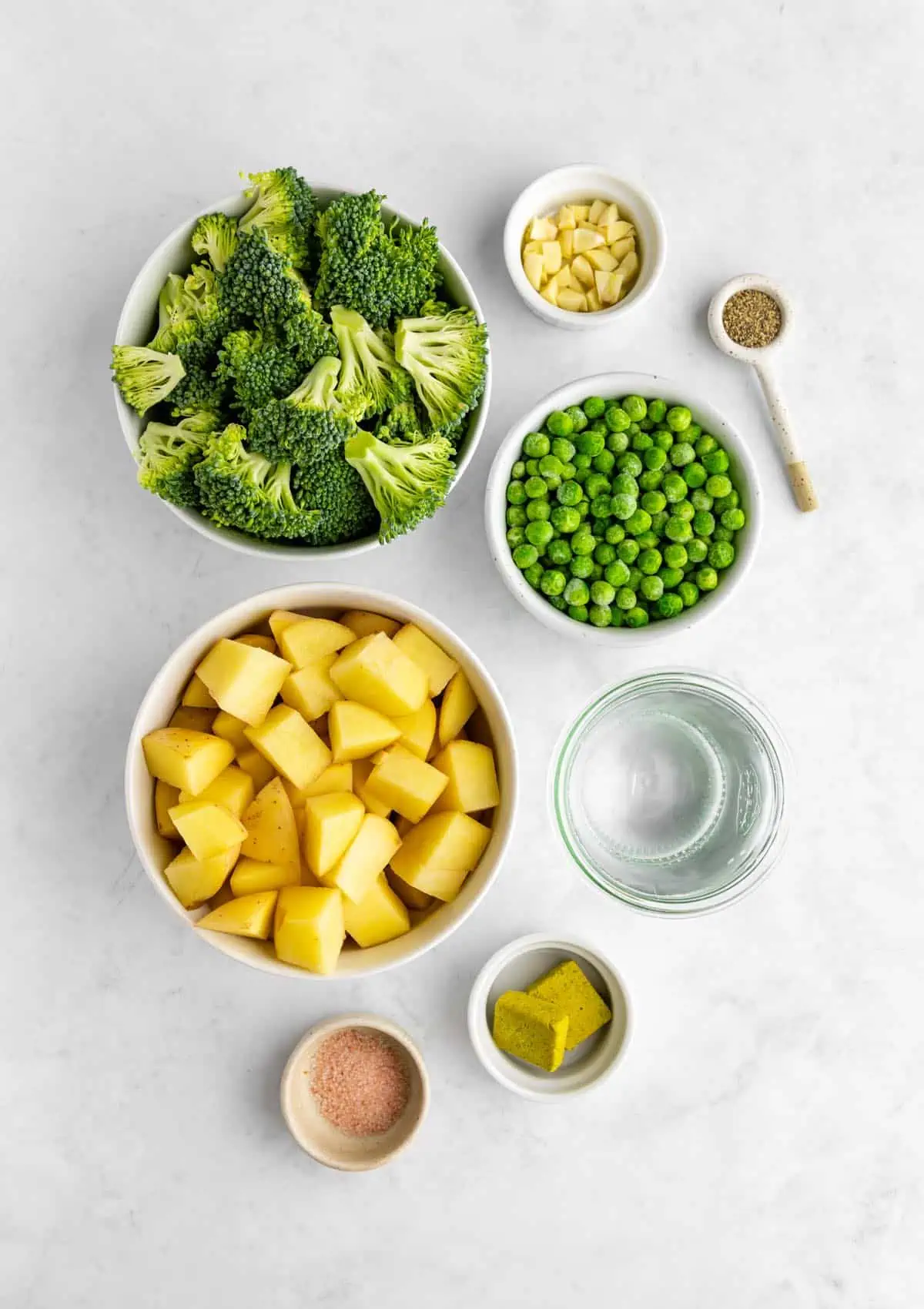 Flatlay photo of the green pea soup ingredients including frozen peas, broccoli, and potatoes. 