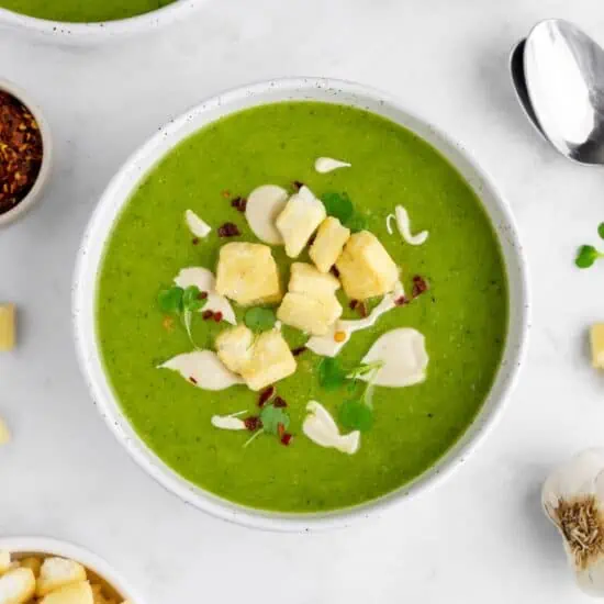 A brilliantly green bowl of vegan creamy green pea soup with broccoli and potatoes.