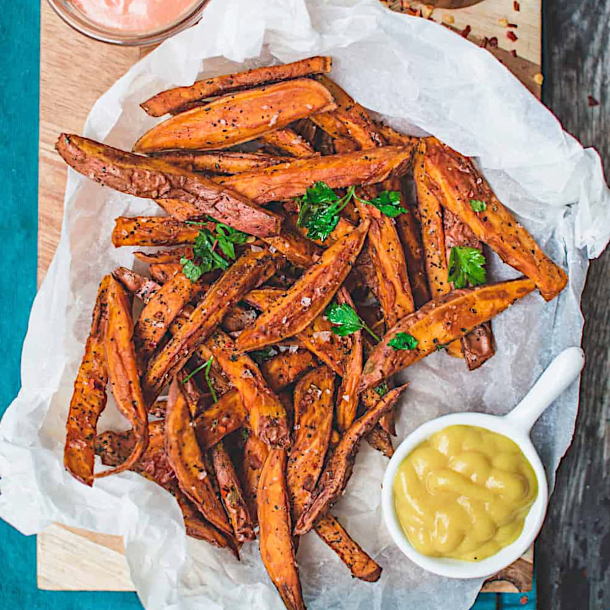 Air fryer sweet potato fries served on parchment paper with a a side of mustard dip.