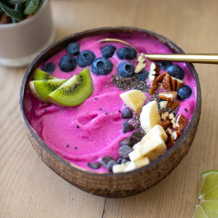 Overhead shot of a pitaya bowl with kiwi slices, blueberries, banana, chia seeds, and chopped nuts.