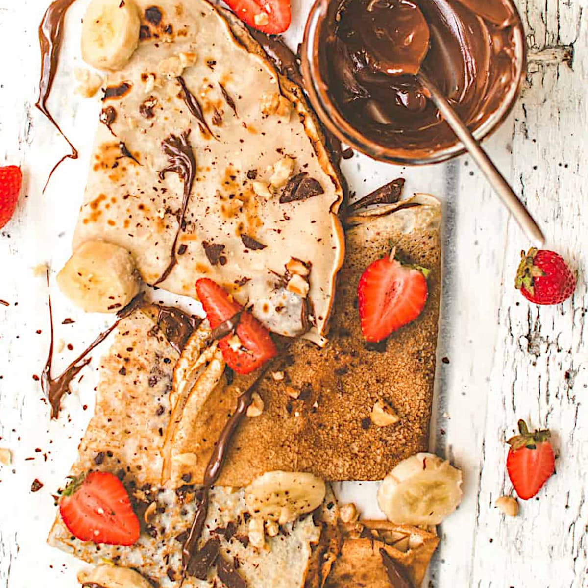 Crepes folded in triangles, topped with vegan nutella and sliced strawberries and bananas.
