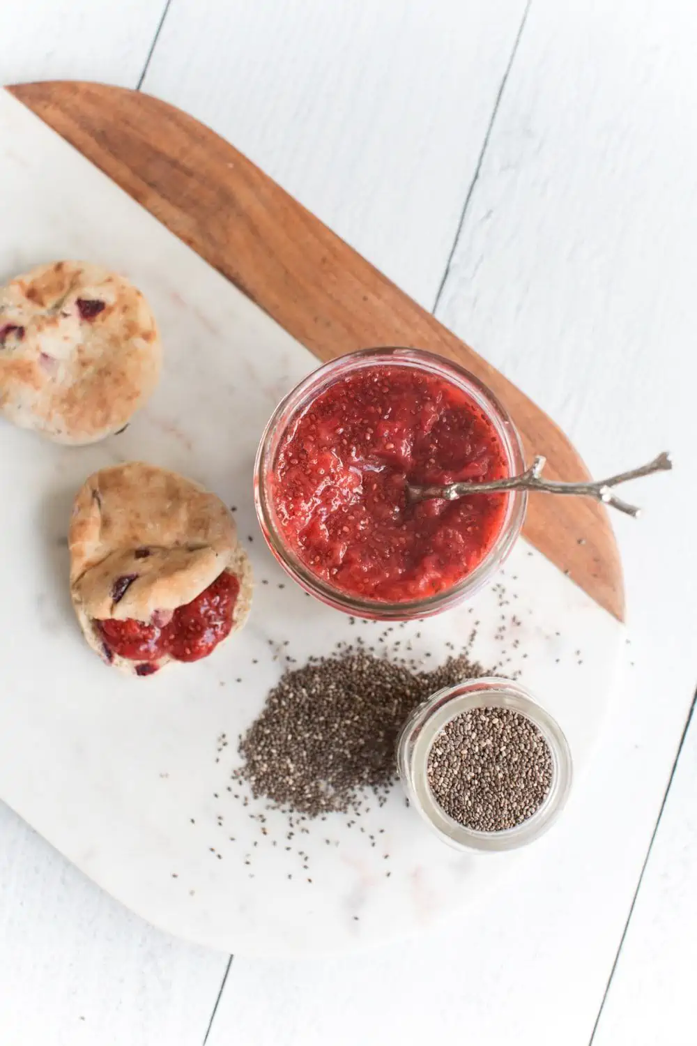 Strawberry chia jam in a jar next to a jar or chia seeds.