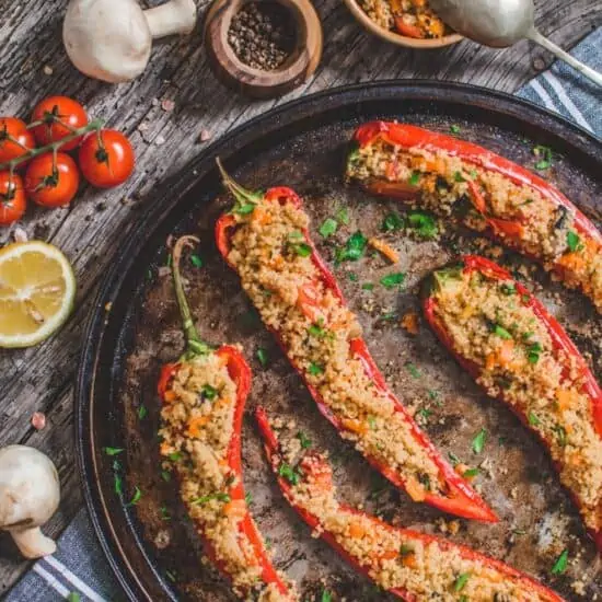 Couscous Stuffed Peppers served on a round serving dish with some ingredients on the side