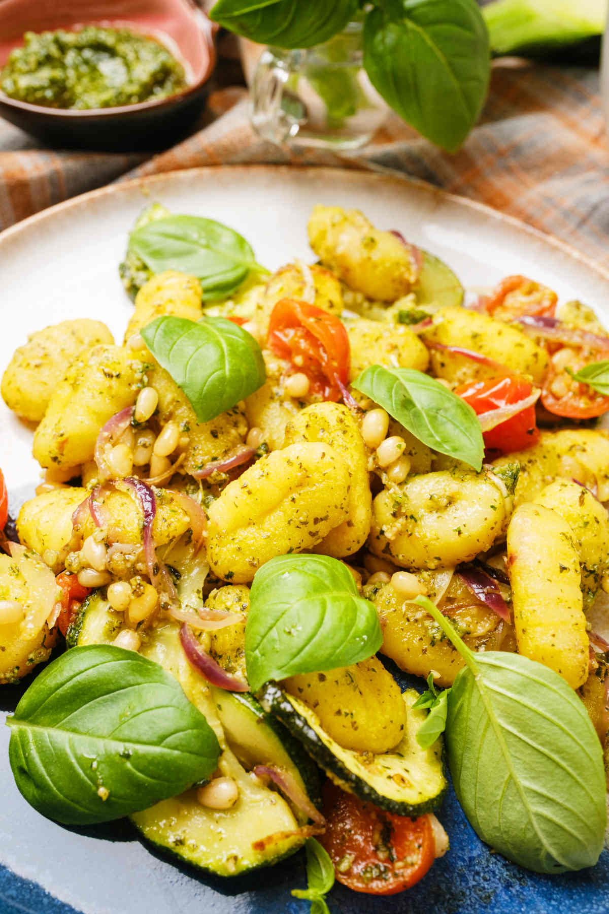 Creamy gnocchi with pesto served on a plated and topped with fresh basil leaves.