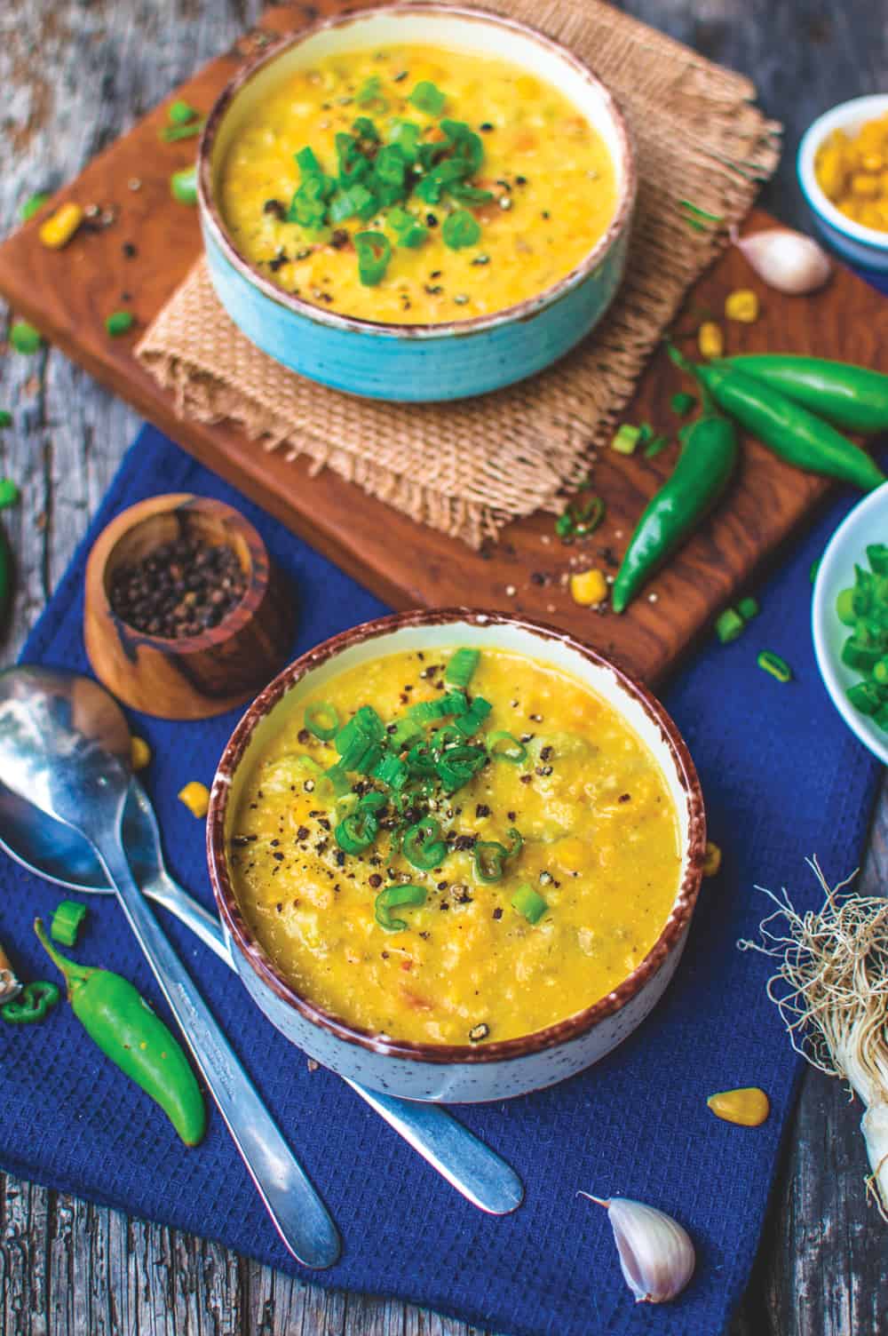 Two Bowls of Corn Chowder Soup served on a table garnished with green onion