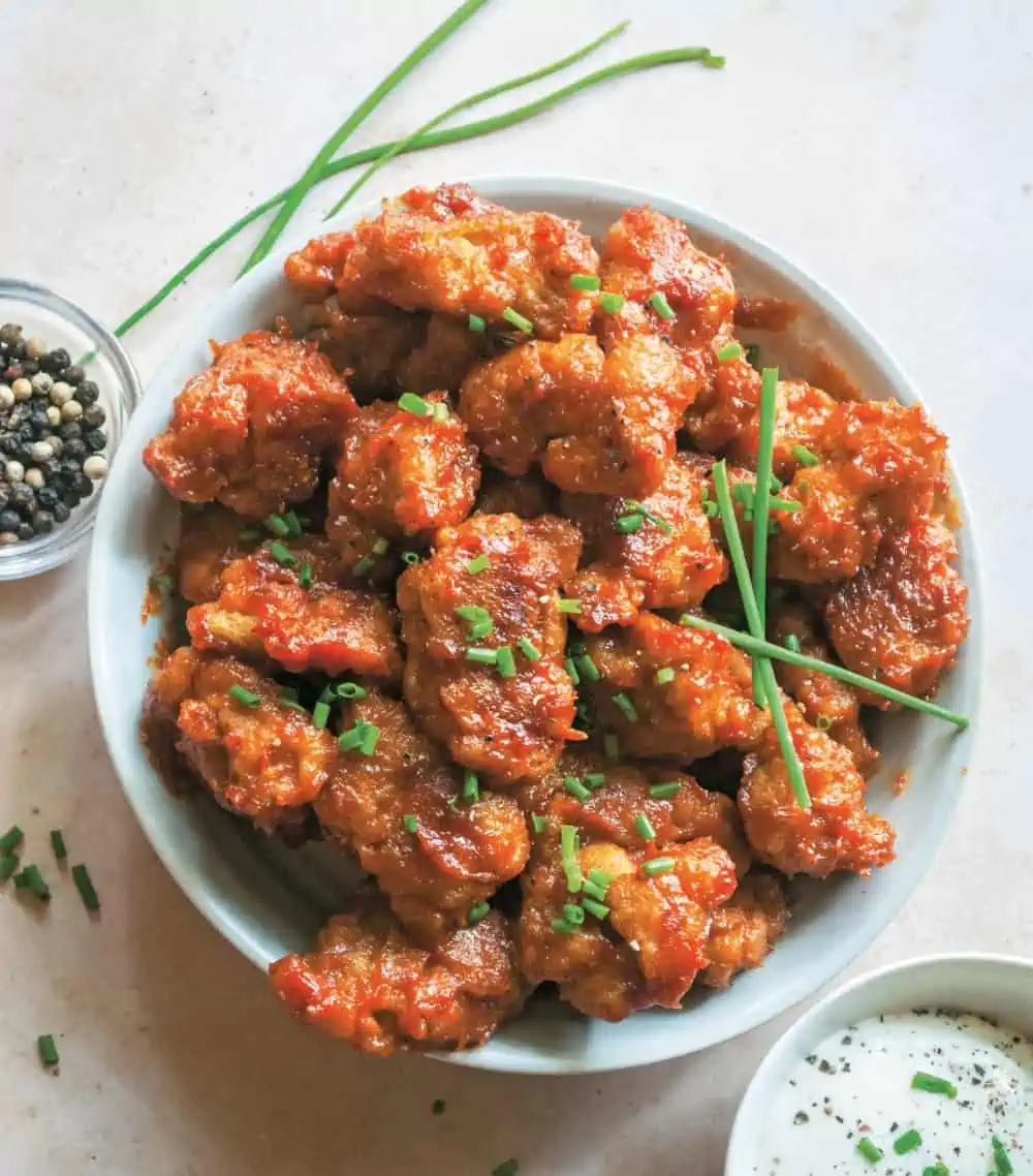 Barbecue chicken seitan wings in a bowl garnished with scallions. 