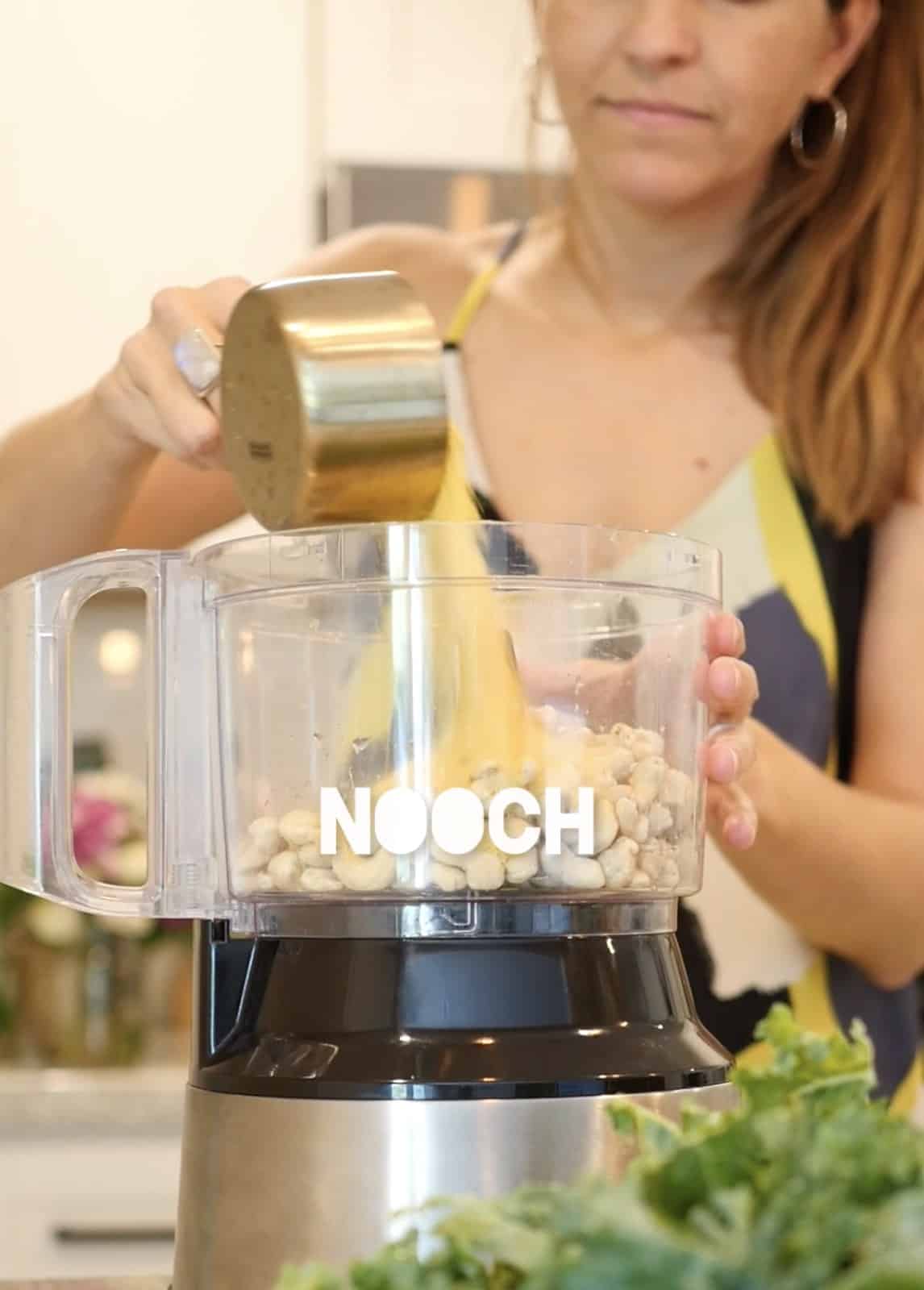 Pouring nutritional yeast into the food processor.
