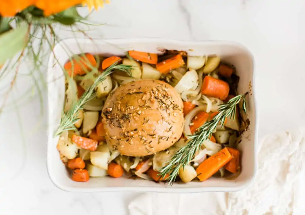 Tofurky roast in a baking dish on top of roasted vegetables.