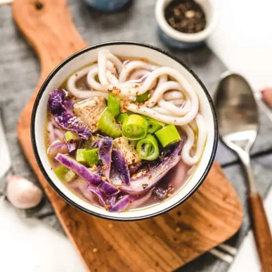 Bowl of Purple Udon Noodle Soup Served over a Wooden Board