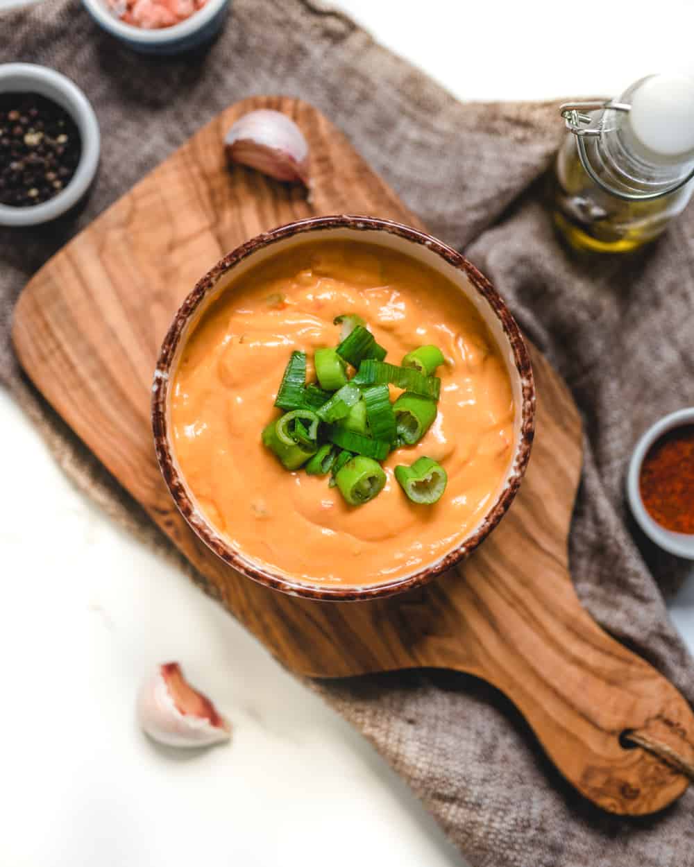 Bowl of vegan queso dip topped with green onions. 