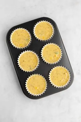 Cornbread muffin batter uncooked in muffin tins.