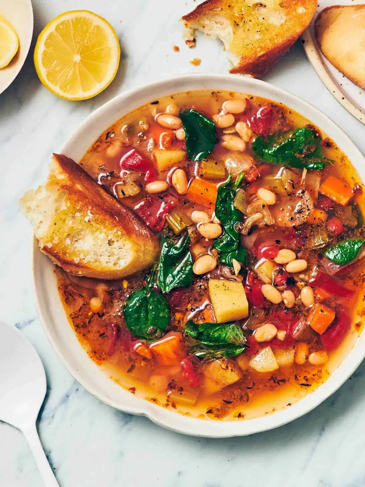 Large bowl of bean soup topped with a slice of crusty bread.