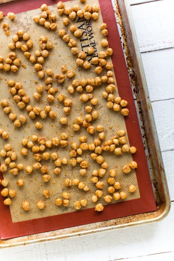 Chickpeas on a baking sheet over a silicone mat with savory spices and oil