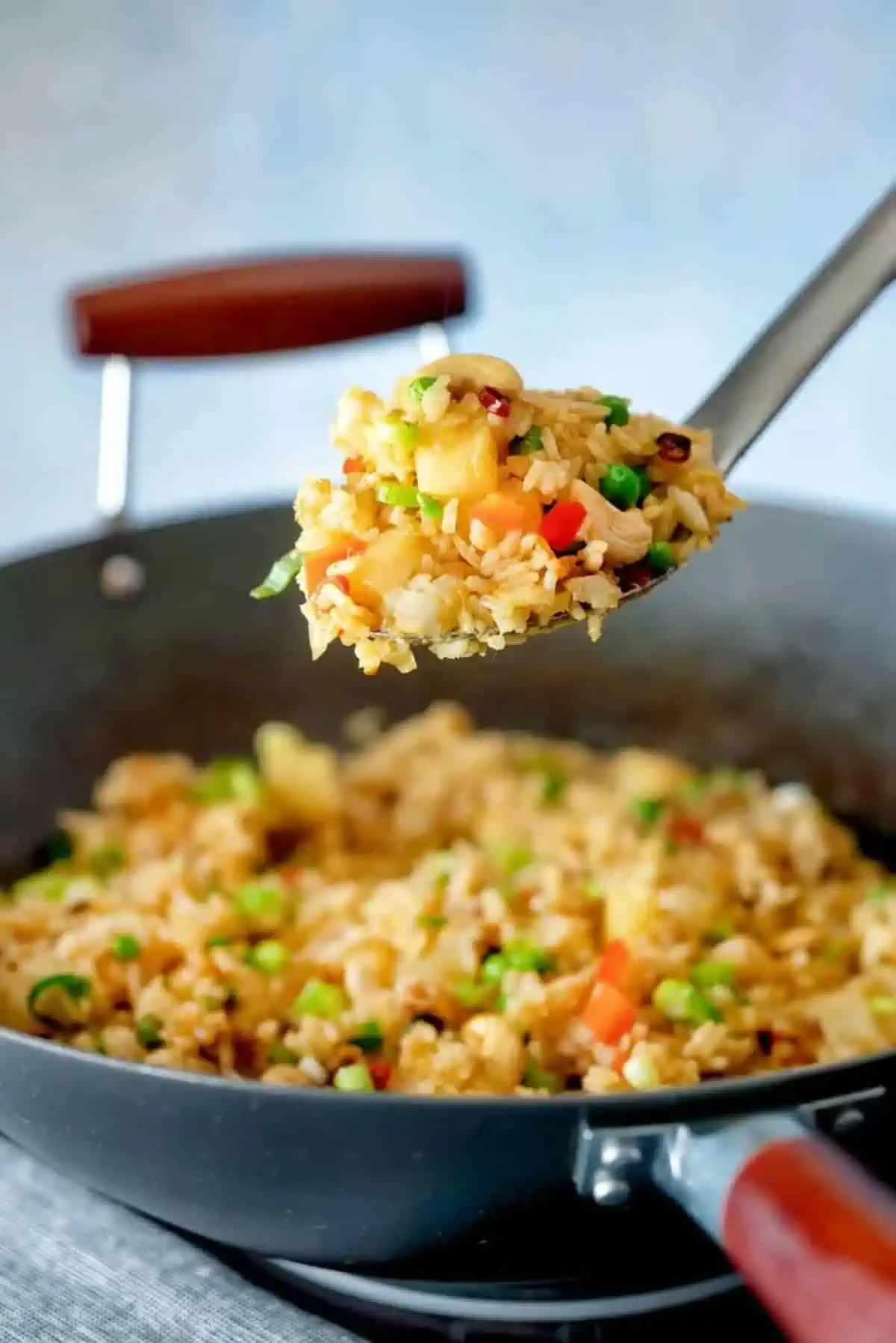 A pot of pineapple fried rice with a large spoon scooping some up.