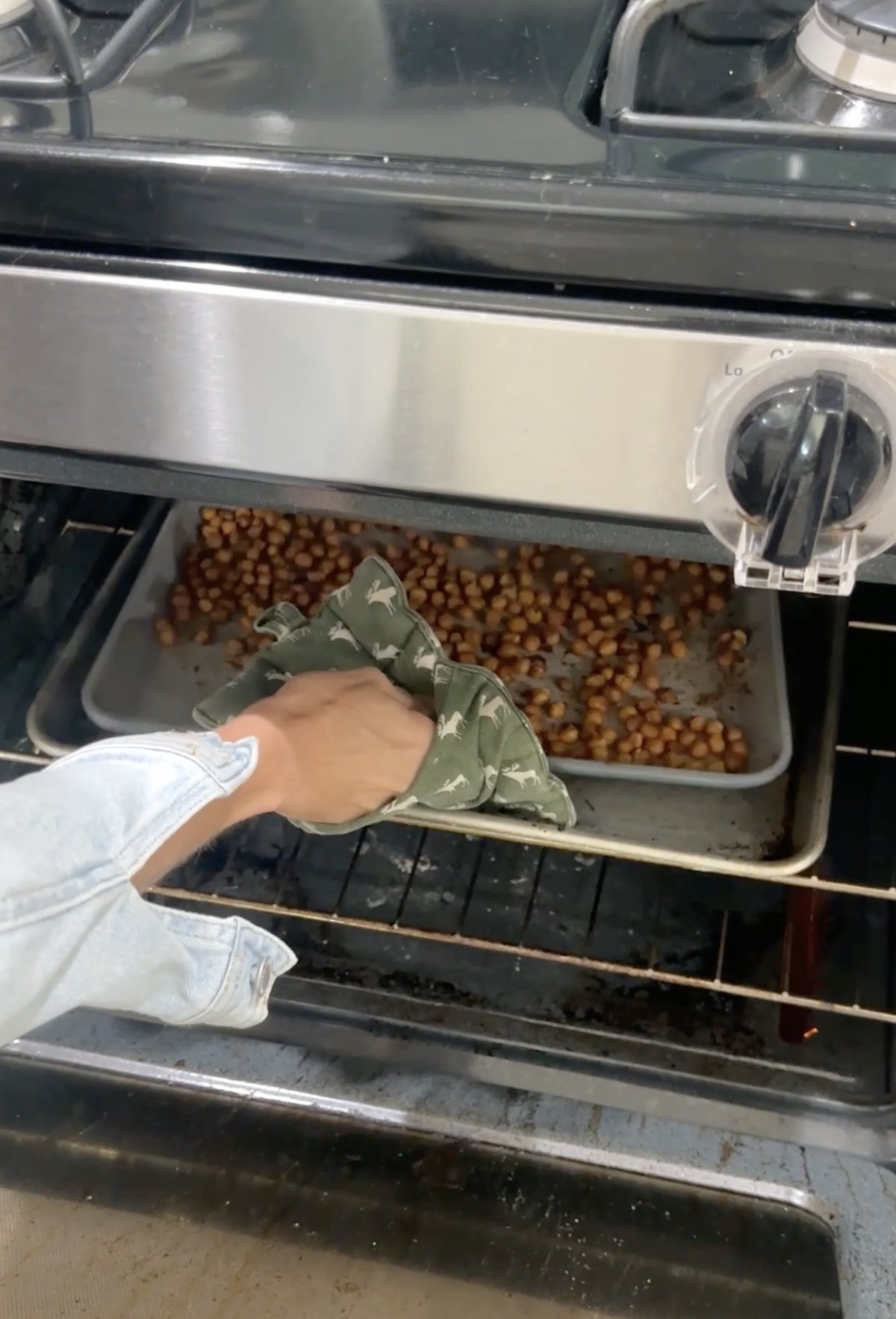 Placing the sheet pan with seasoned chickpeas into an oven.