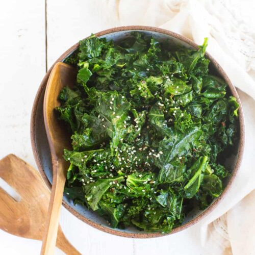 Bowl of Kale with Sesame with wooden serving spoons