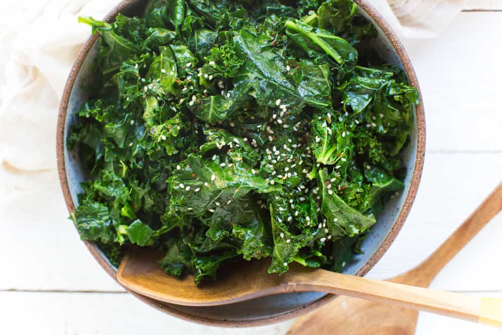 Bowl of Sauteed Kale with Sesame with wooden serving spoons Close Up