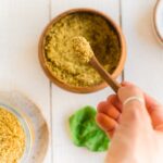Spicy chipotle seasoning in a bowl with a hand scooping some into a small wooden spoon.