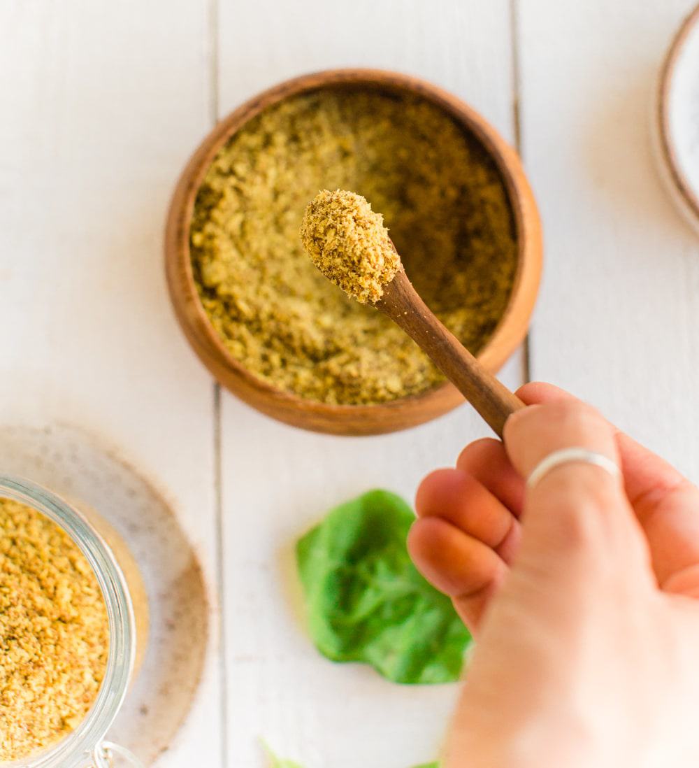 Spicy chipotle seasoning in a bowl with a hand scooping some into a small wooden spoon.