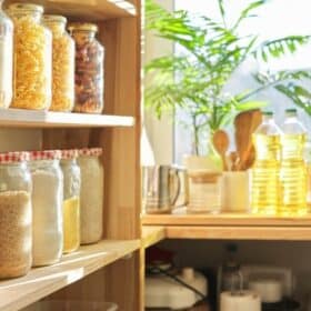 Wooden pantry shelves with glass jars filled with various dry goods.