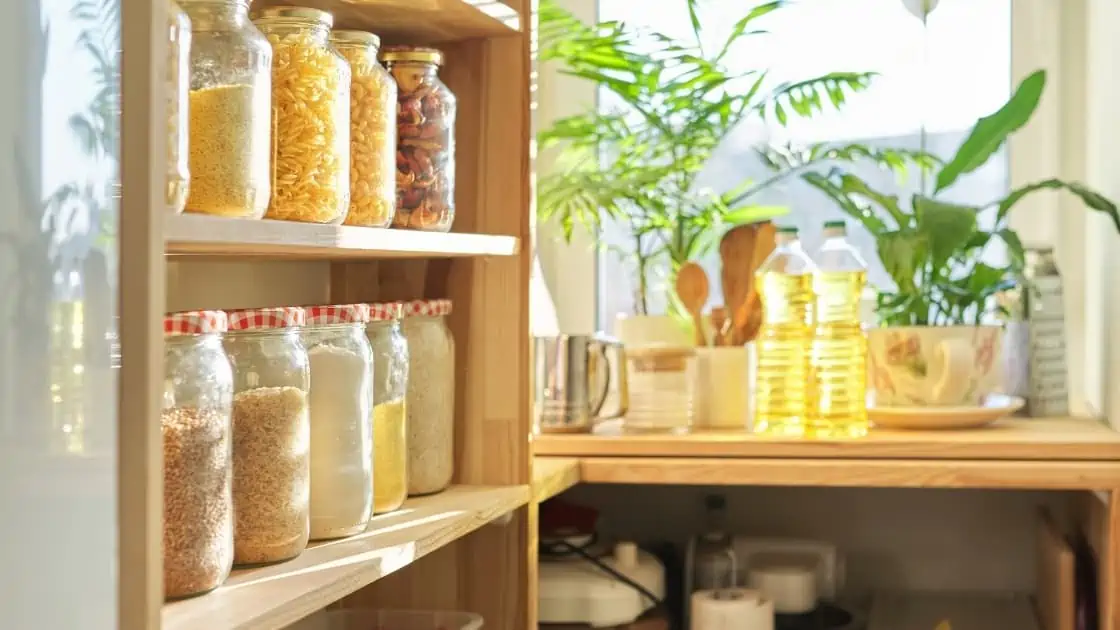 Wooden pantry shelves with glass jars filled with various dry goods.