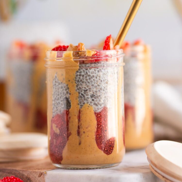 Peanut butter and jelly chia pudding layered in a jar with strawberry jam compote, vanilla chia pudding, and peanut butter.