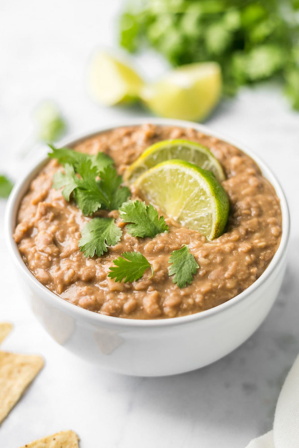 Vegan refried beans in a serving bowl with cilantro and lime slices.