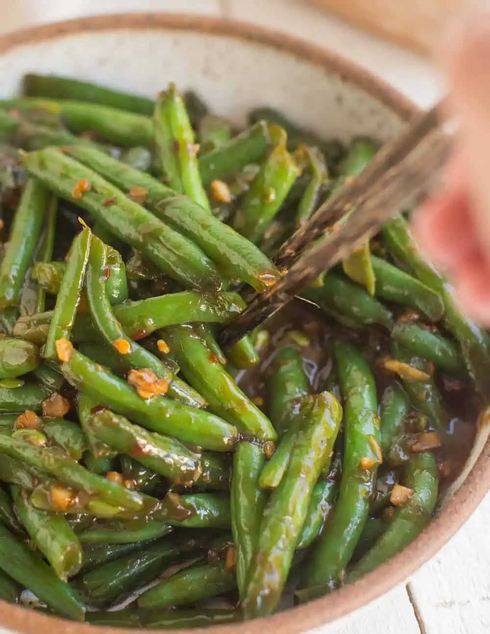 Green beans in a bowl with chopsticks reaching in.