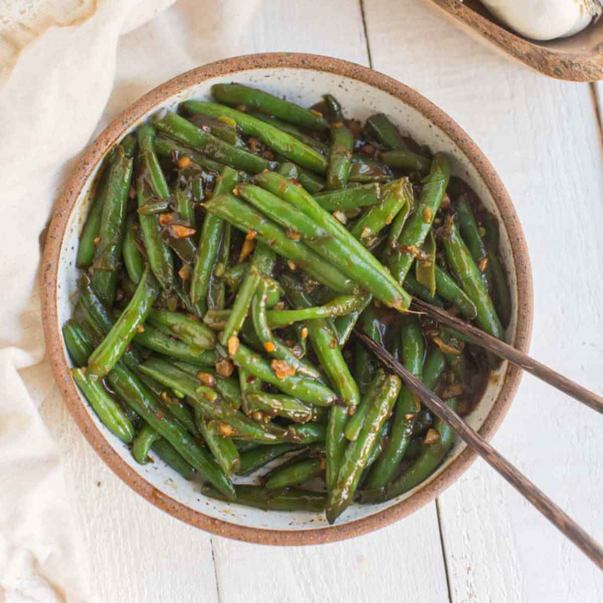 Chinese green beans in a serving bowl with chopsticks.