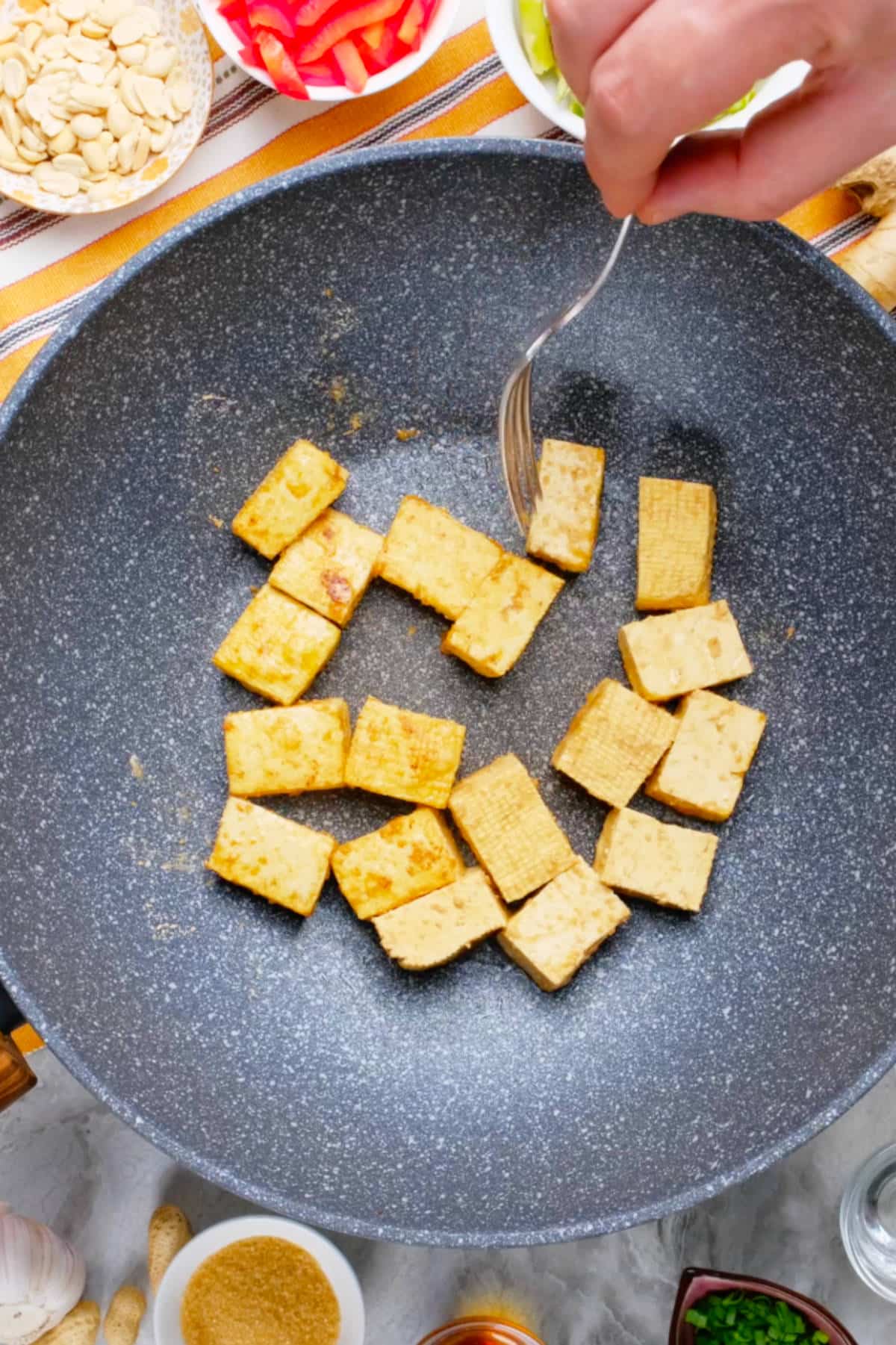 Marinated tofu cube sauteeing in a nonstick pan.