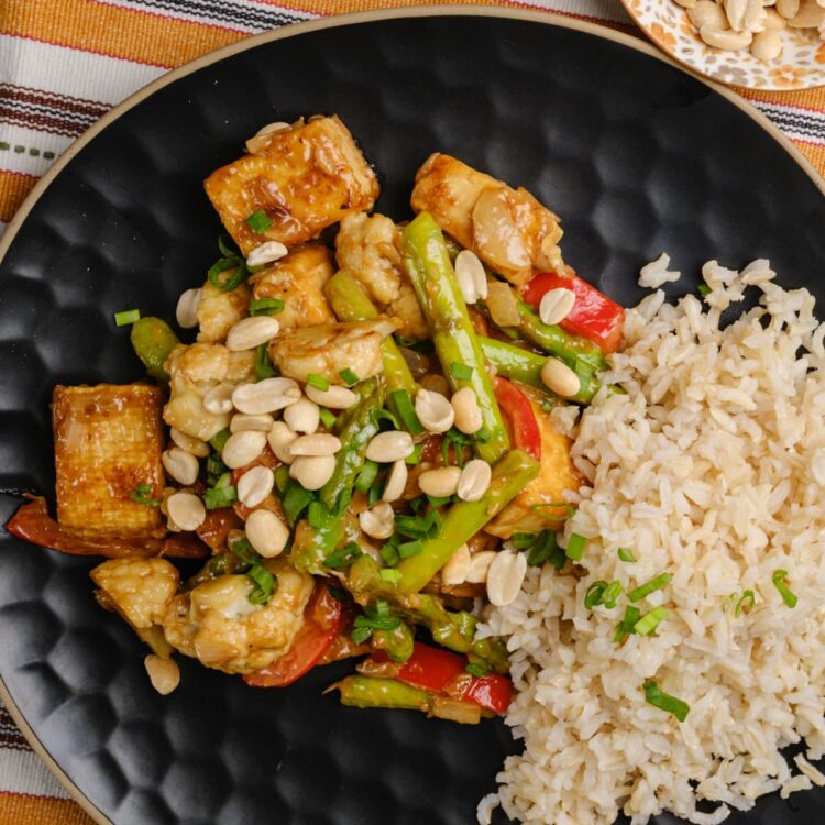 A plate of tofu peanut stir fry served with a side of rice.